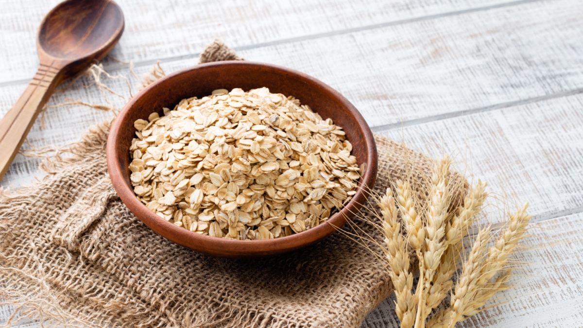Rolled oats, healthy breakfast cereal oat flakes in bowl on wooden table