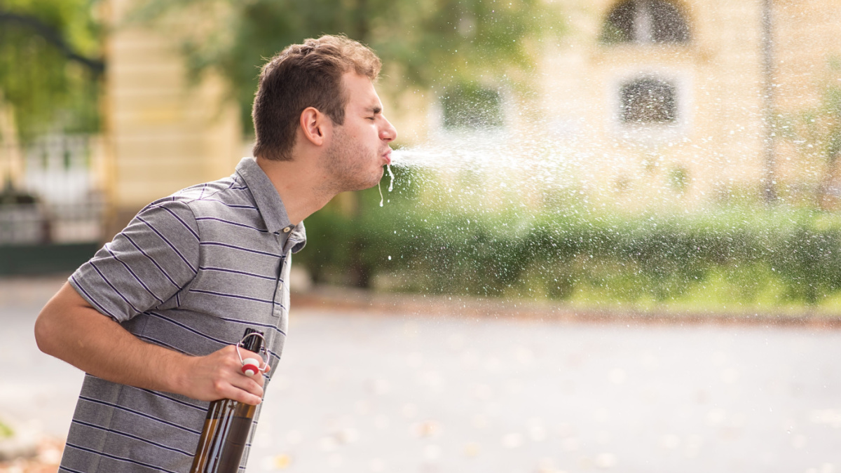 Young man spit out alcohol in the park.
