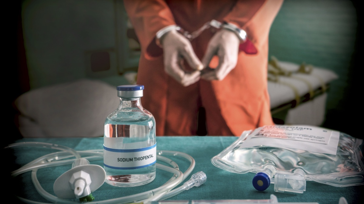 Prisoner handcuffed to death by lethal injection, vial with sodium thiopental and syringe on top of a table, conceptual image