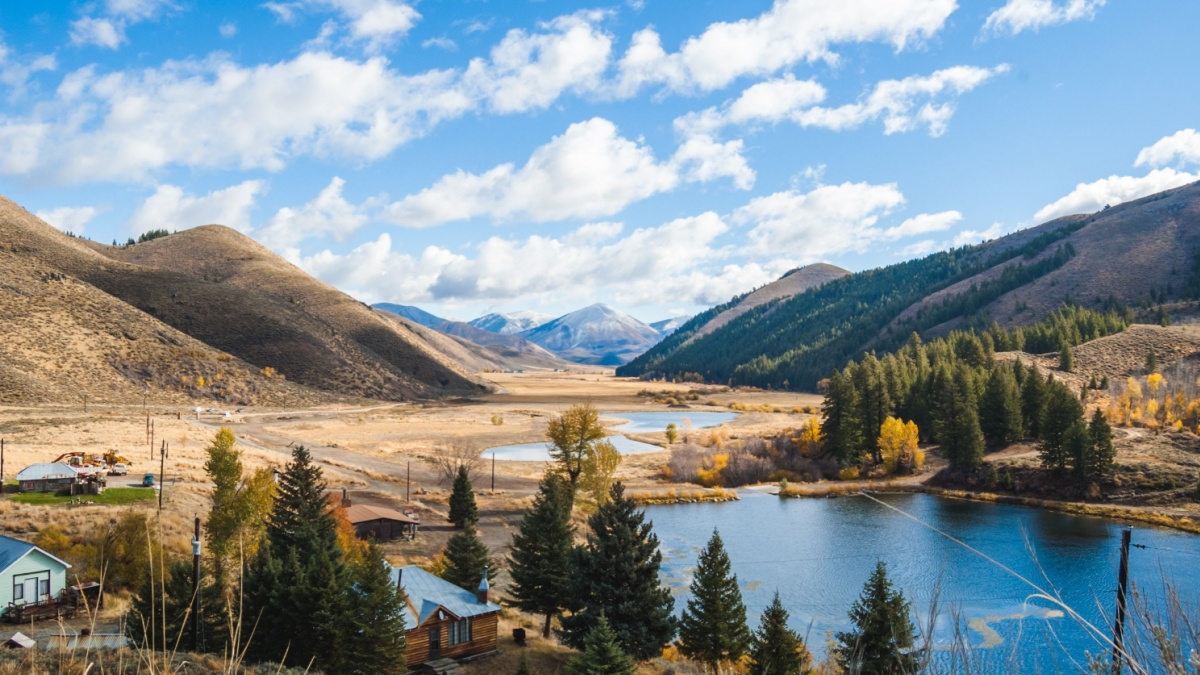 Partly cloudy blue sky over mountain landscape, lake, and countryside properties. Deer Creek in Hailey, Idaho, USA.