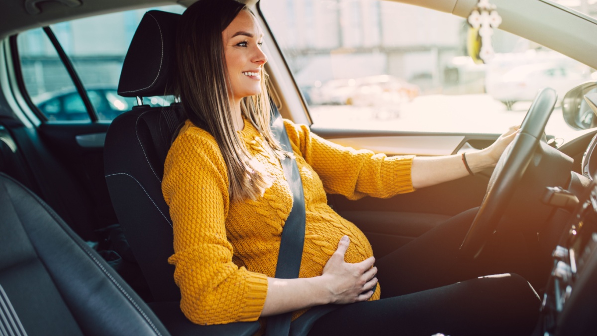 Pregnant woman driving with safety belt on in the car.