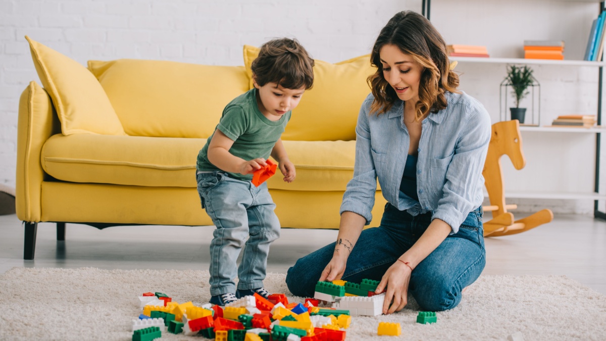 Mother and son playing with lego on carpet in living room