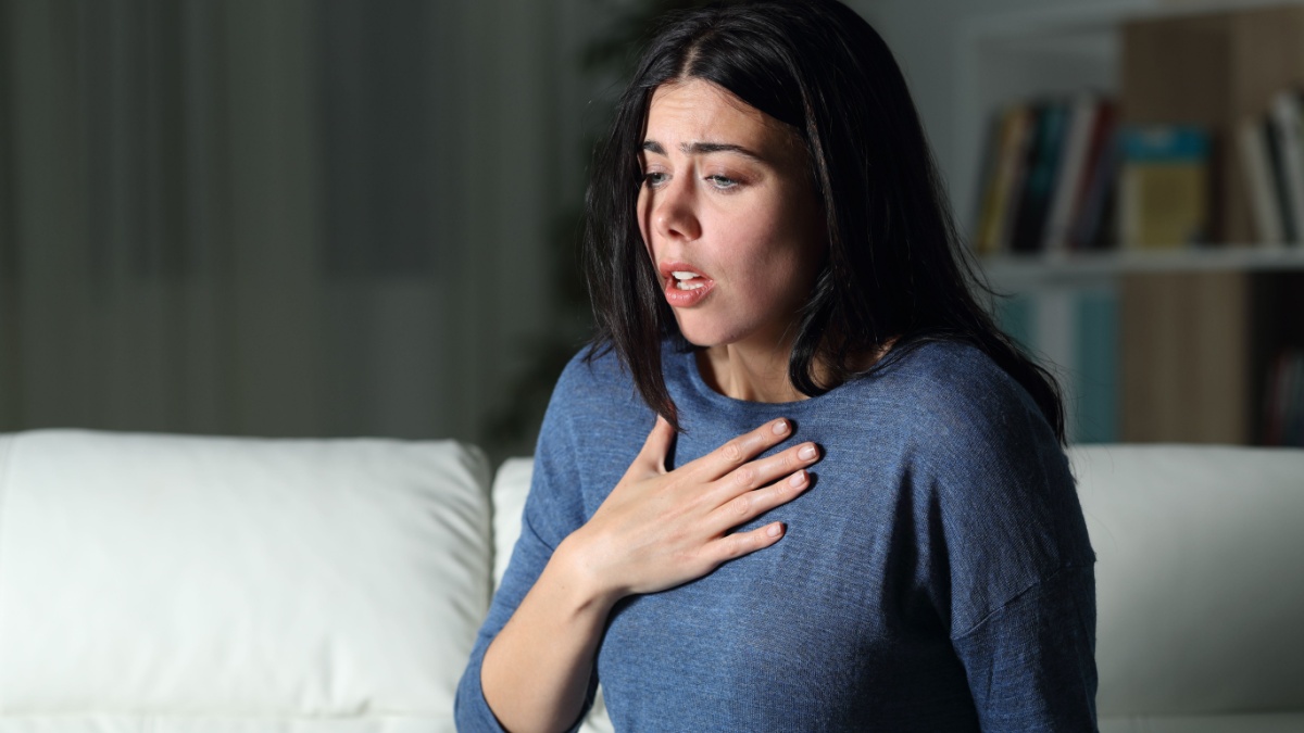 Woman suffering an anxiety attack alone in the night on a couch at home.