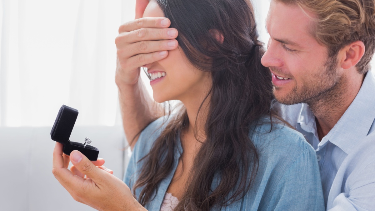 Man hiding his wifes eyes to offer her an engagement ring for a marriage proposal