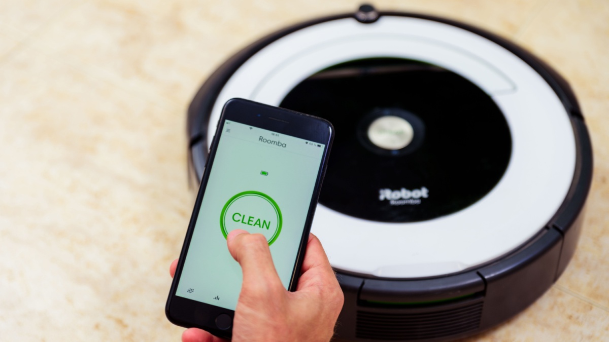 Man hand activating the roomba irobot vacuum cleaner from the application. Smart life concept, smart city, smart home.