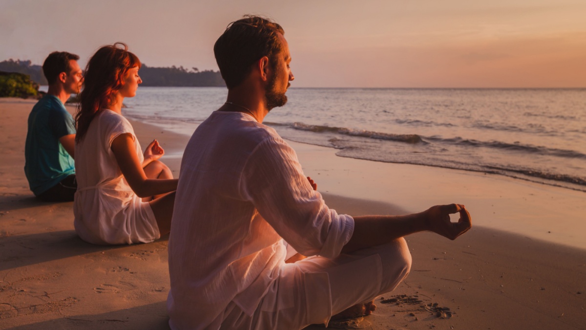 group meditation, people practicing yoga on the beach, relaxation and breathing excercises