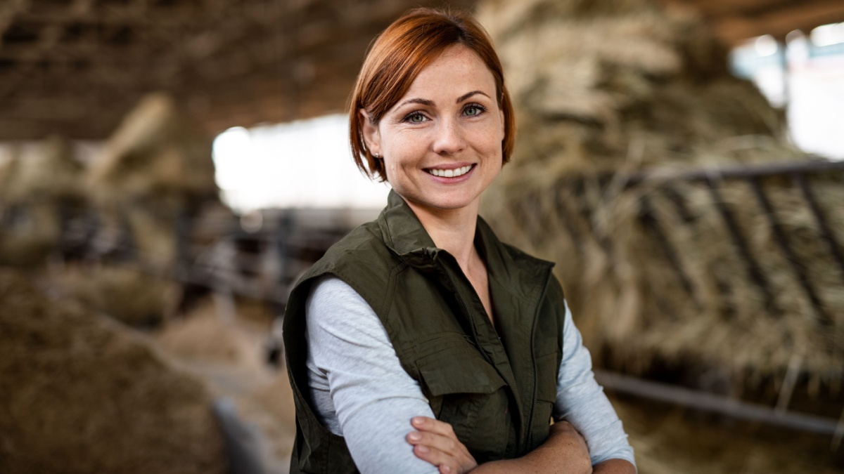 Woman worker standing on diary farm, agriculture industry.