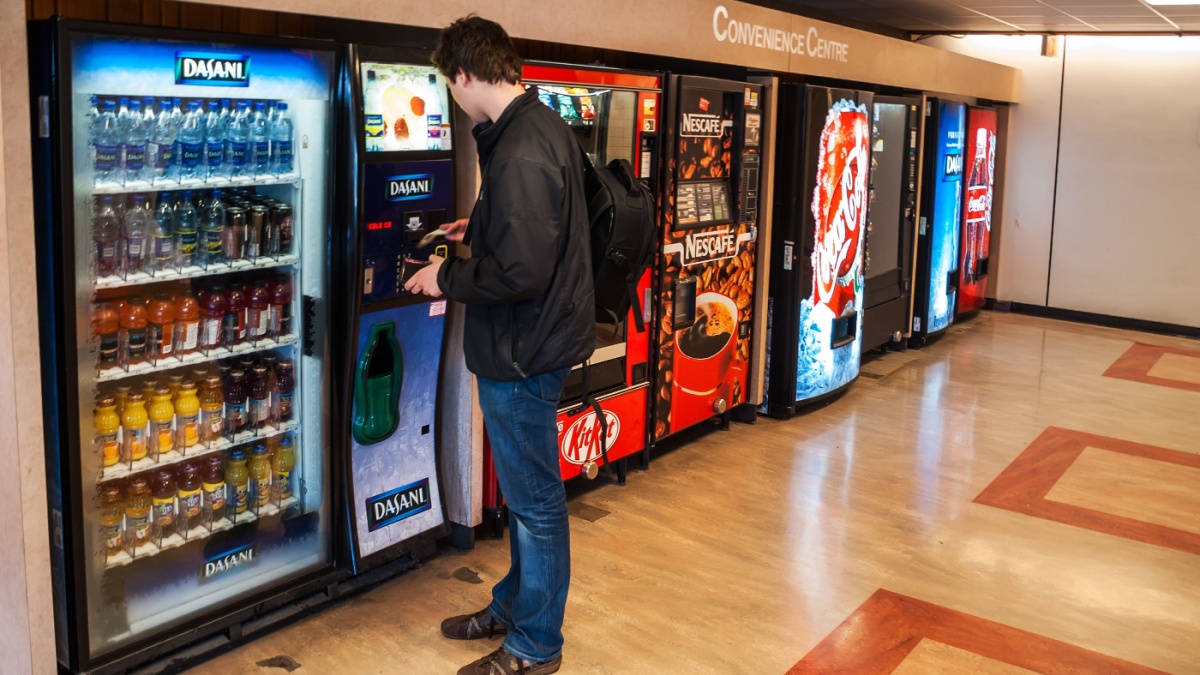 Unidentified male student paying for the drinks from the vending machine at Simon Fraser University Convenience Centre.