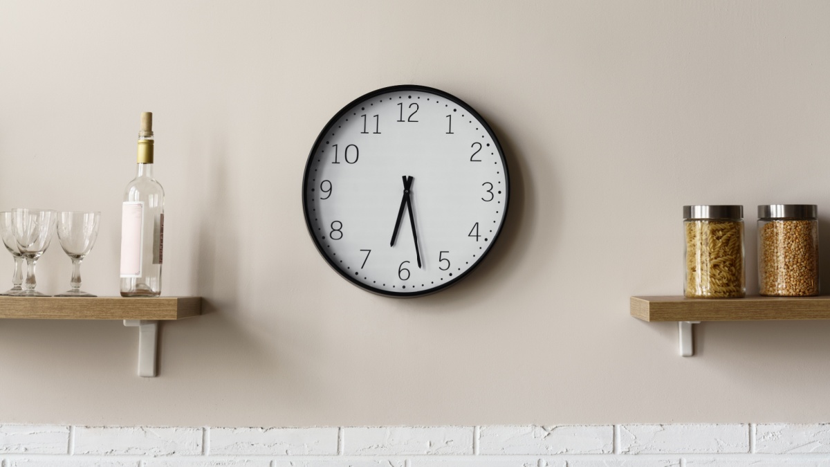 Round wall clock between wooden kitchen shelves