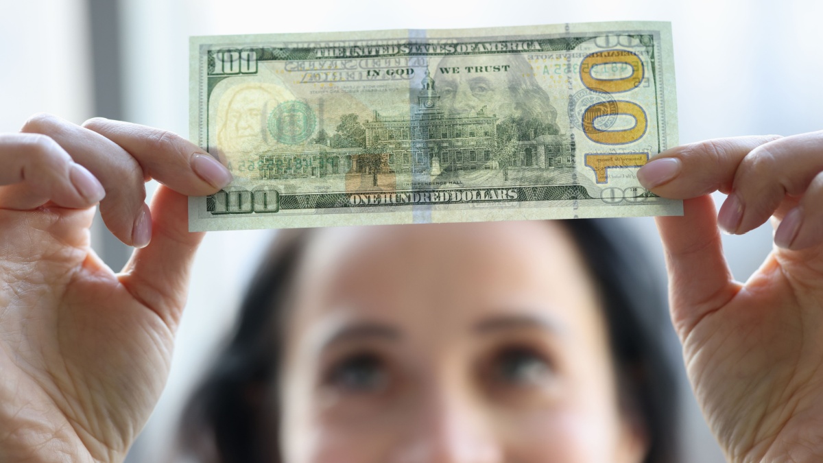 Woman holding dollar bill and looking at it with watermarks closeup.
