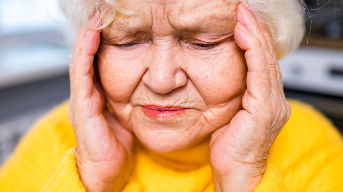 Headshot of aged woman feeling head ache at home.