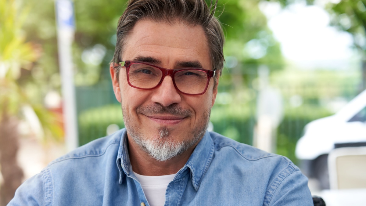 Outdoor portrait of white older man with gray hair, wearing eyewear.