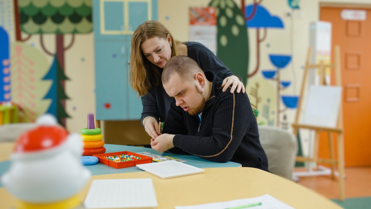 A female psychologist works with an adult boy with autism in the office. The concept of autism