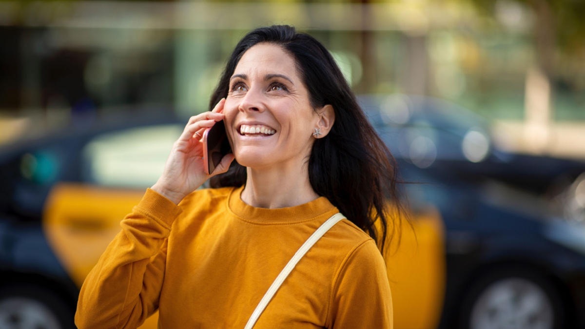 Smiling caucasian woman talking on smart phone outdoors in city.