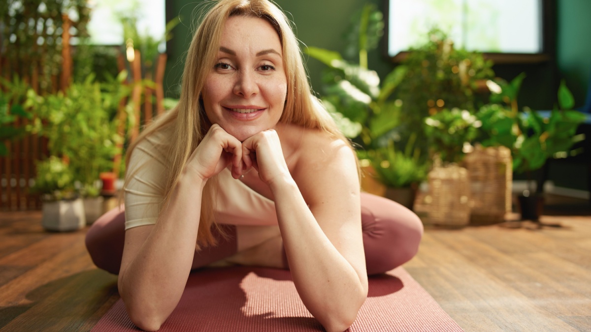 Portrait of happy modern woman with yoga mat doing yoga in the modern green house.