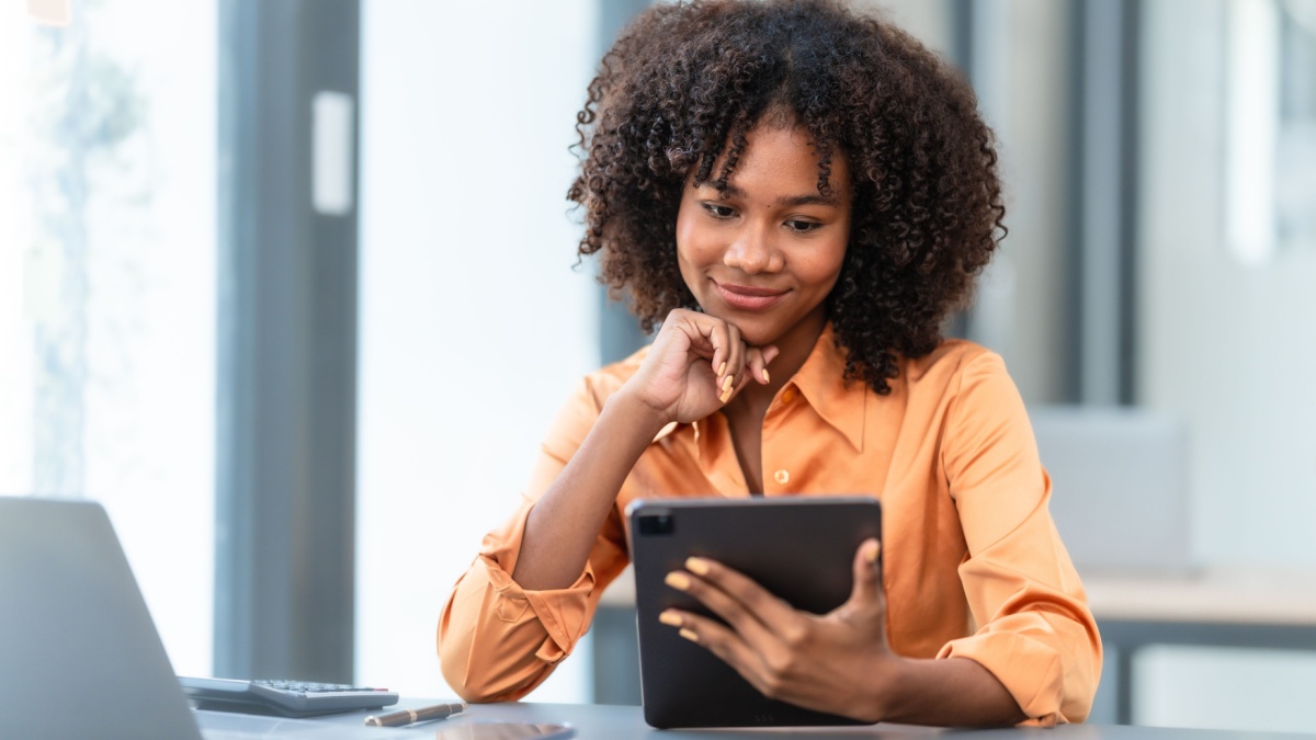 Using laptop computer, Young pretty african american business woman bookkeepers working with balance sheet yearly reports to calculate tax and online consult in modern office.