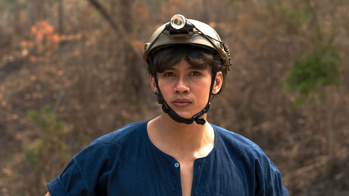 Portrait fireman wearing safety hat with bushfire in forest background.