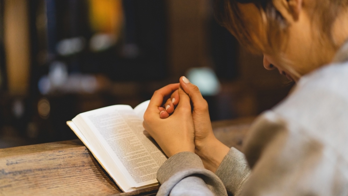 Christian woman reading bible in an ancient Catholic temple. Reading the Holy Bible in temple. Concept for faith, spirituality and religion. Peace, hope, dreams concept