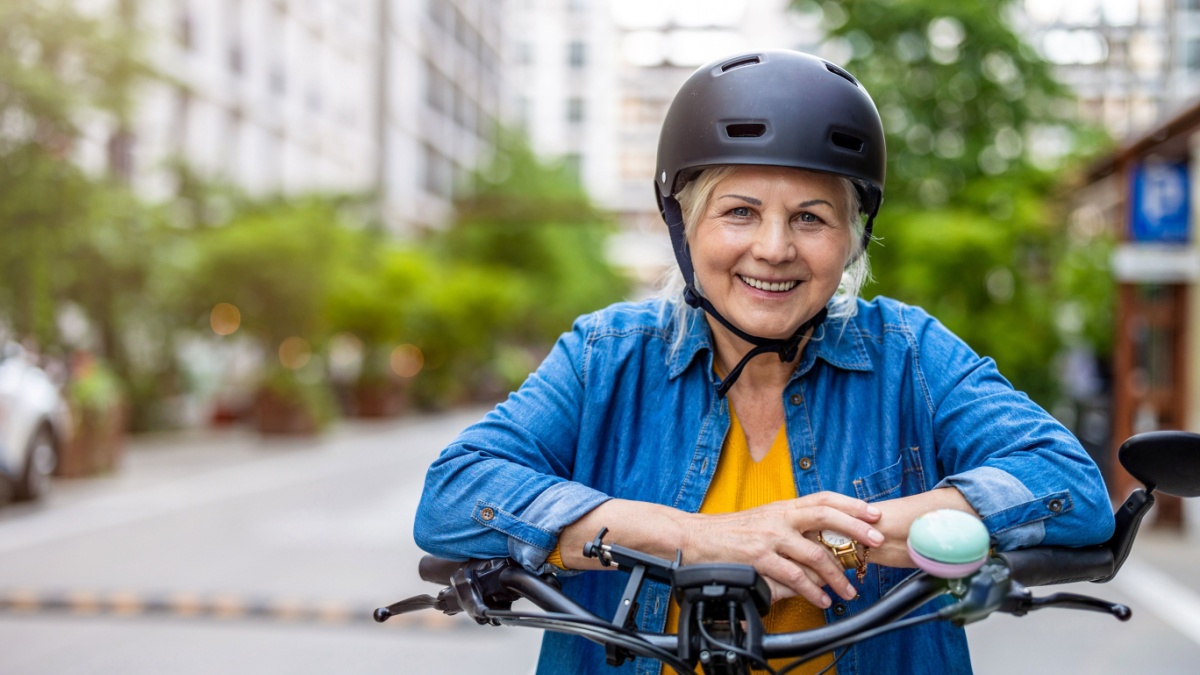 Portrait of senior woman wearing helmet while riding bicycle in the city.