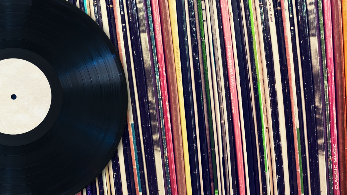 Vinyl record with copy space in front of a collection of albums (dummy titles), vintage process