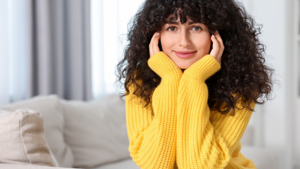 Young woman in stylish yellow sweater indoors, space for text.