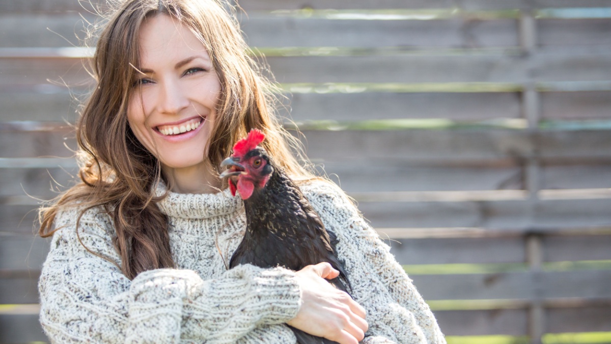 Rural beauty woman holding hen, focus on woman, daylight.
