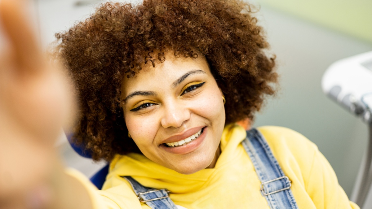 The black woman with afro hair happily takes a selfie with the mobile phone.