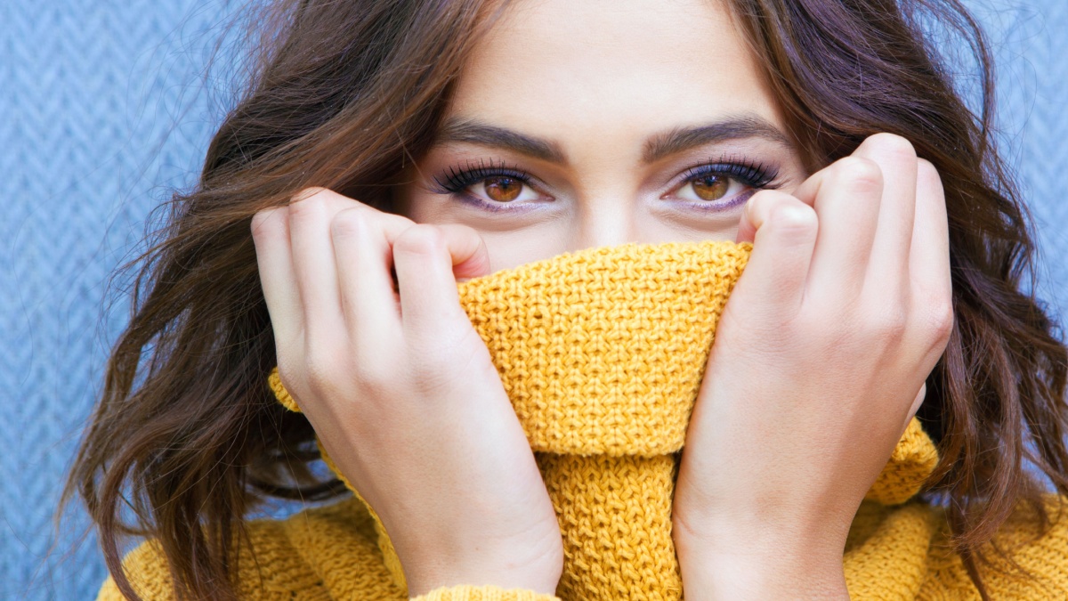 Beautiful natural young shy brunette woman with smiling eyes wearing knitted sweater.