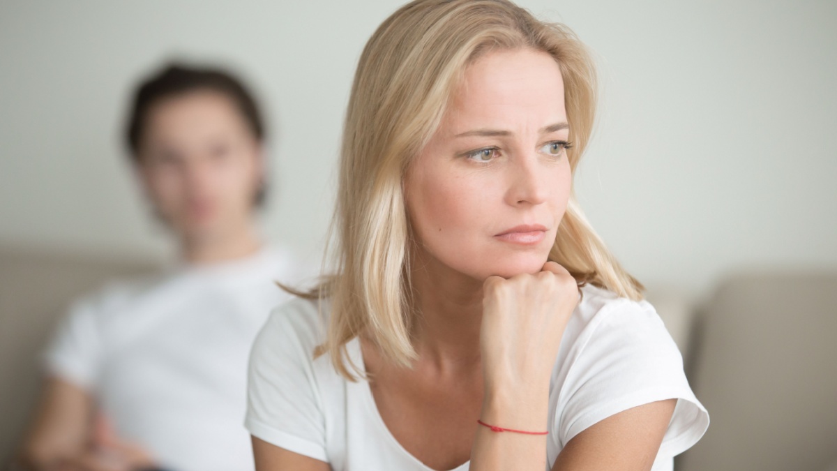 Serious sad woman thinking over a problem, man sitting aside, end of long-term relations, an alcoholic, drug addicted partner, poor conflict management skill.