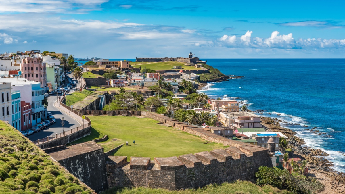 View of ocean towards San Felipe del Morro from Castillo de San Cristobal with castle wall and grass fields in between