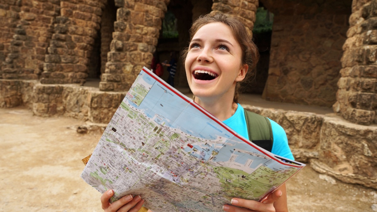 Woman traveling on holidays in Europe. Tourist girl using travel map during her hike. Hiking, Travel in Spain.