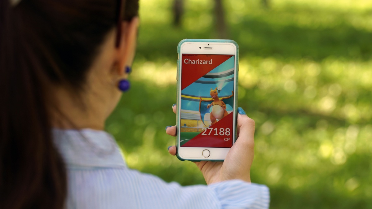 woman playing pokemon go on his iphone 6s plus. pokemon go multiplayer game with elements of augmented reality. Charizard