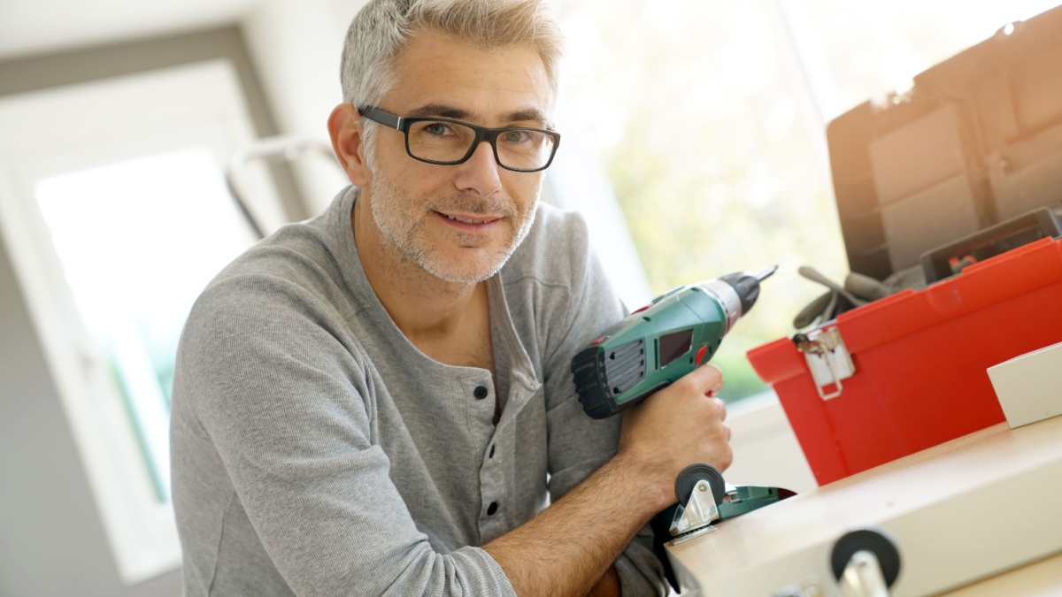 Portrait of cheerful man with electric drill.