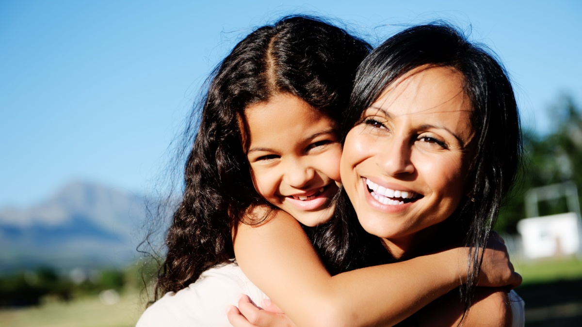 mom and daughter have fun outdoors, smiling and piggyback in the sunshine.