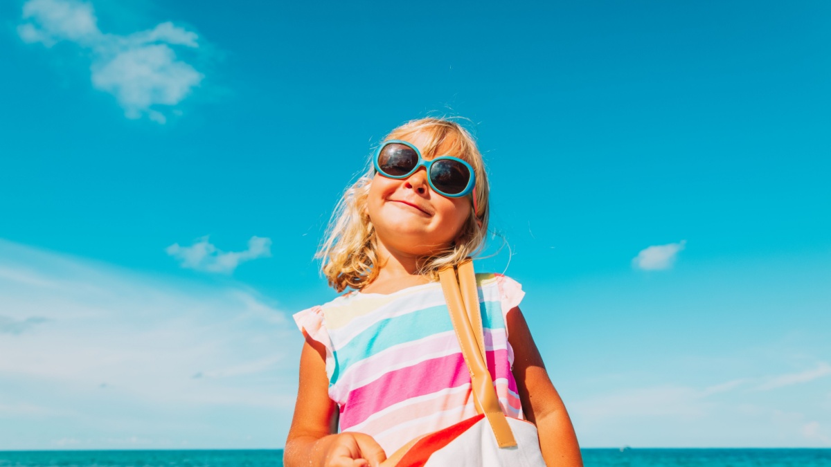 cute little girl with big bag on beach.
