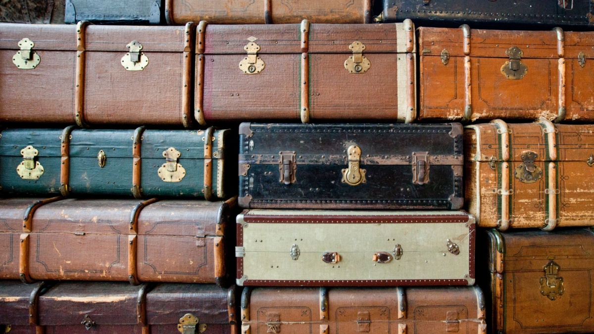 Photo of old suitcases of the beginning of the 20th century. Suitcases stand on top of each other, in different colors and sizes.