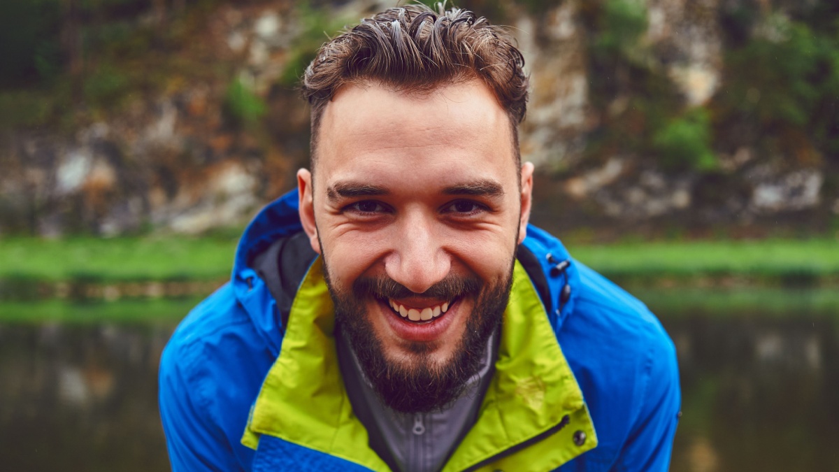 Portrait of a young, bearded man, on, against a background of wildlife. The concept of expedition, adventure and camping life.