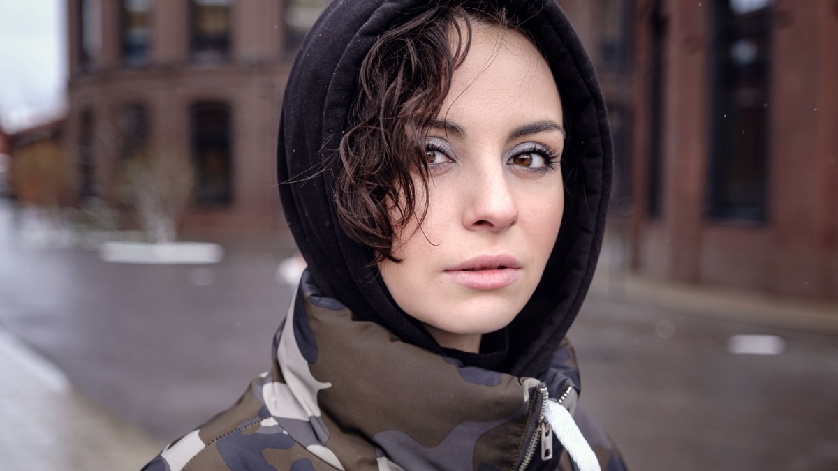 Stylish brunette woman in trendy apparel looking and enjoying winter in city. Outdoor lifestyle portrait of pretty young girl, wearing hipster swag grunge style.