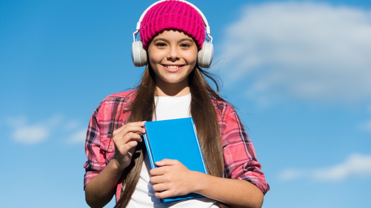 Learn language different way. Happy child wear headphones on blue sky.