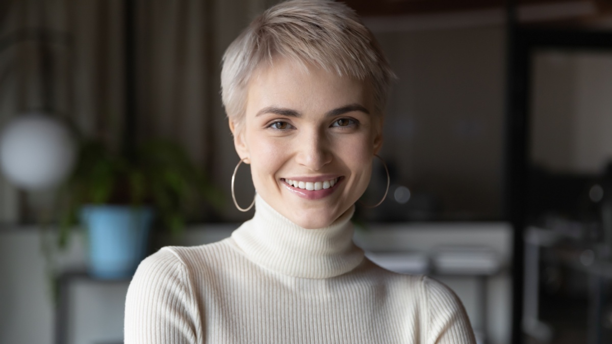 Head shot profile portrait of young happy short haired blonde businesswoman in modern office.