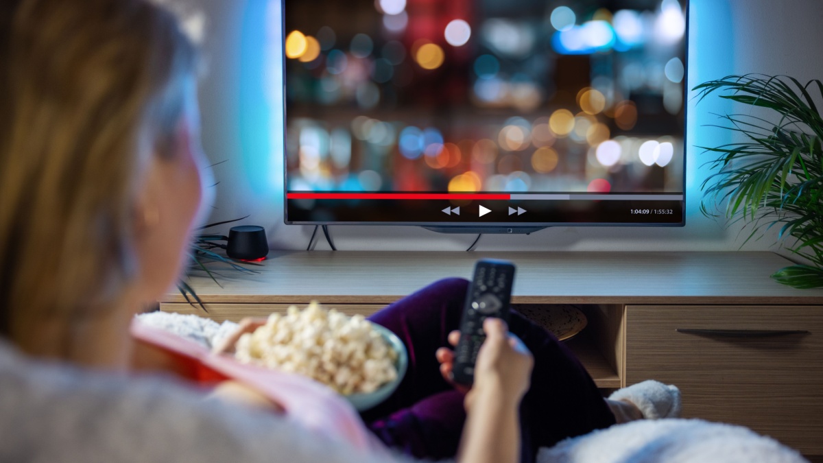 Woman relaxing at home in evening and watching TV.