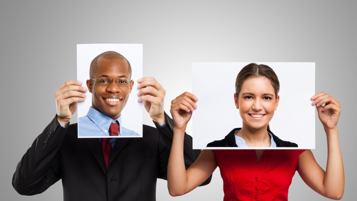 Man holding a portrait of another smiling person.