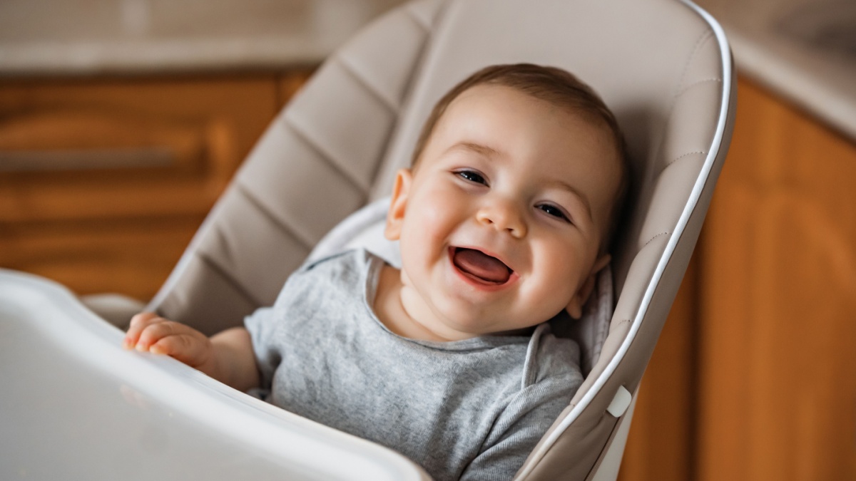 Happy baby sitting in high chair in a kitchen. Healthy nutrition for kids. Children , the safety of children. Little boy play and ready to have lunch at home.