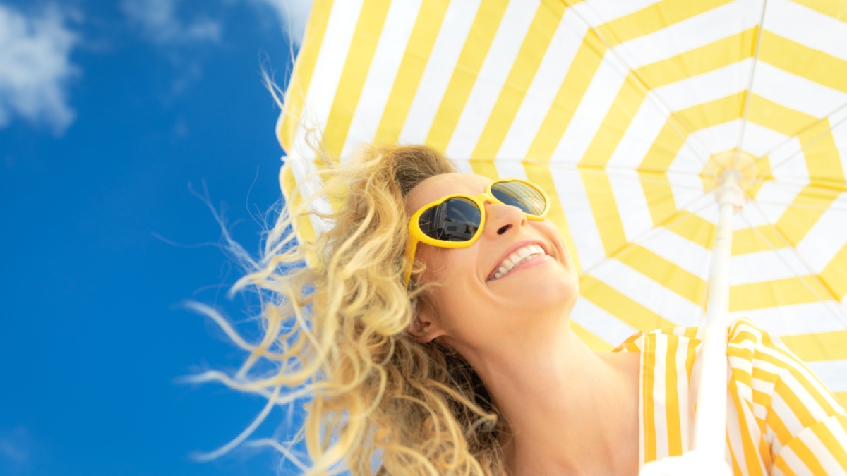 Beautiful woman on summer vacation. Low angle view portrait of happy person against blue sky background.