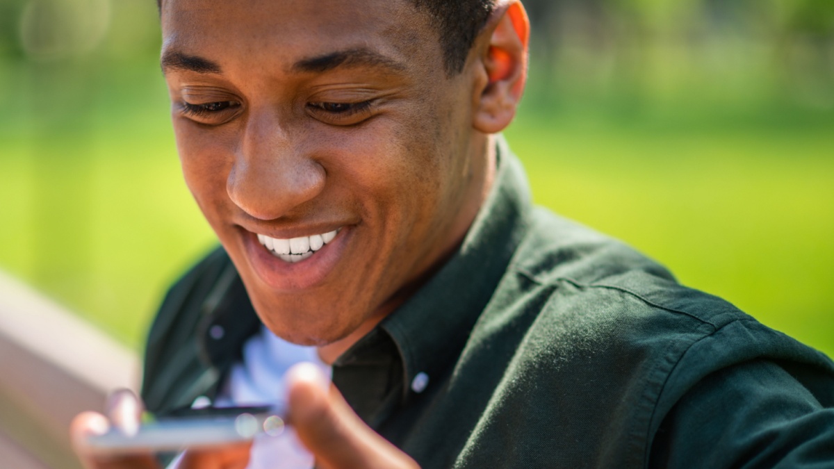 Face of man saying message on smartphone.