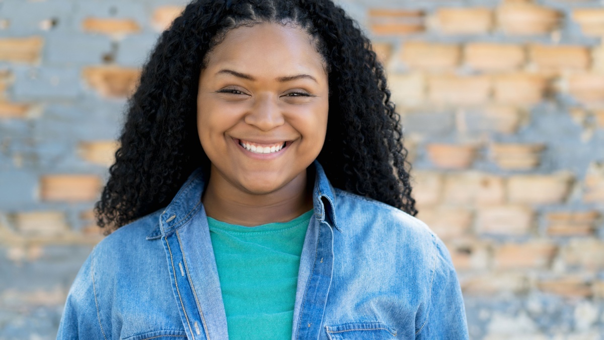 Laughing black young adult woman outdoor in city.