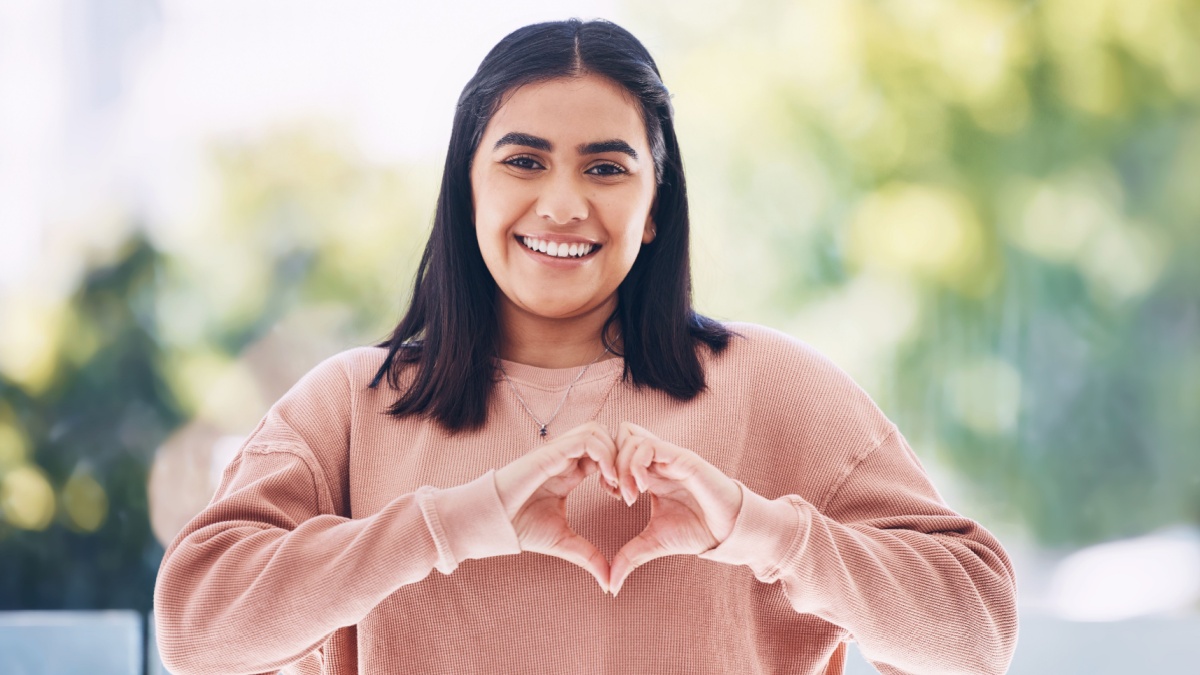 Portrait, heart hands and young woman for self care, cardiology wellness and gen z support for women health.