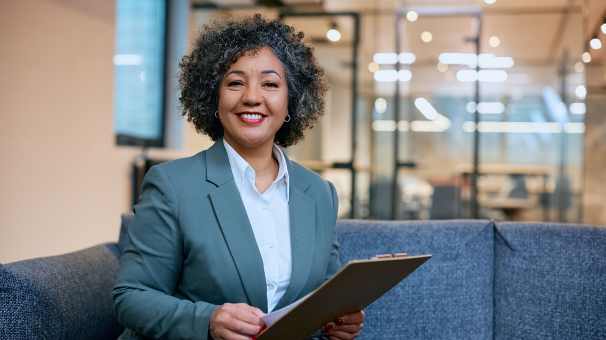 Happy female insurance agent in the office looking at camera.