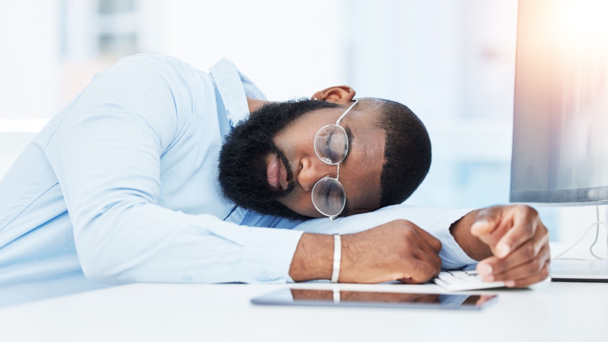 Sleeping, burnout and tired businessman in office overwhelmed by deadlines with fatigue at desk.