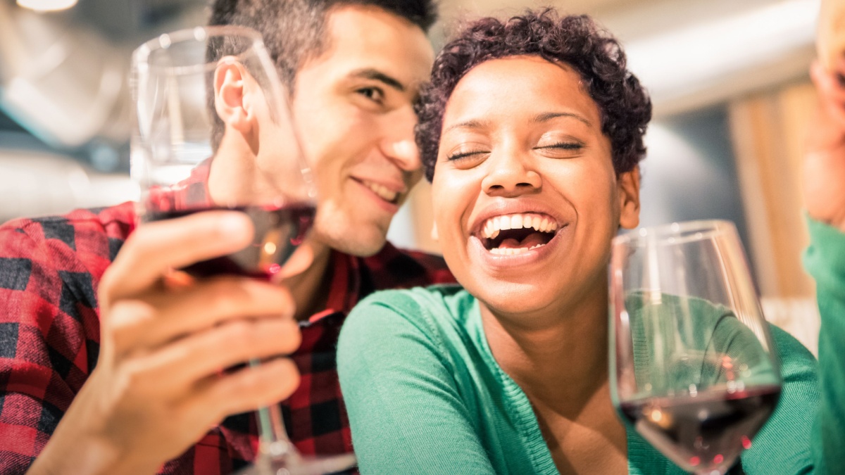 Happy multiracial couple of lover drinking red wine at fashion restaurant .